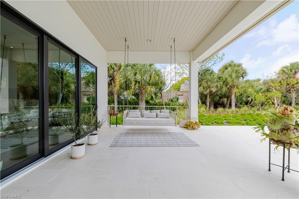 Expansive covered patio featuring a slatted ceiling, light-toned tile flooring, and a porch swing
