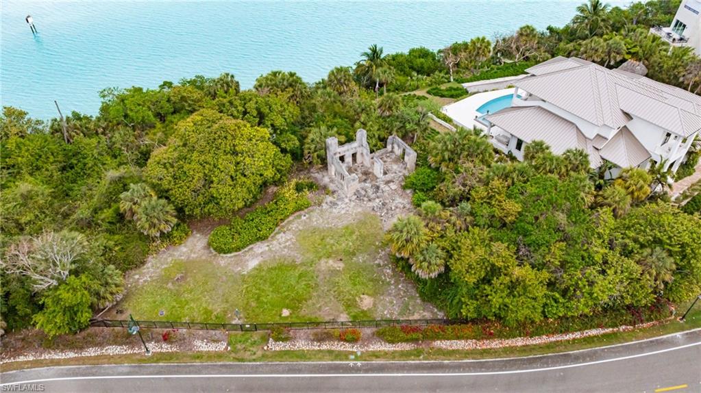 Waterfront property featuring extensive natural landscaping, a partial structure, and frontage on a paved road