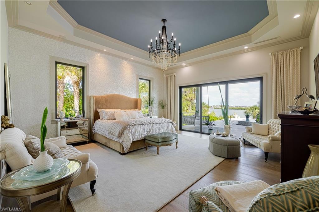 Spacious interior featuring a coffered ceiling with a chandelier, hardwood-style flooring, sliding glass doors to the outdoor space, and large windows