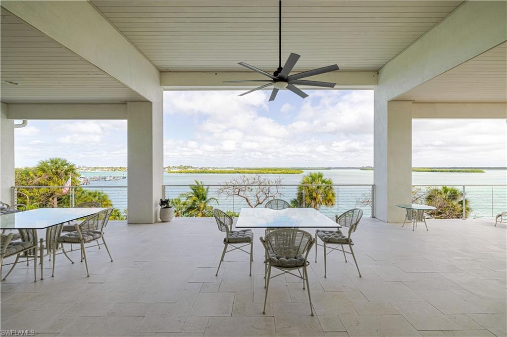 Expansive covered patio featuring light-toned large format tile flooring, a slatted ceiling, and an oversized ceiling fan