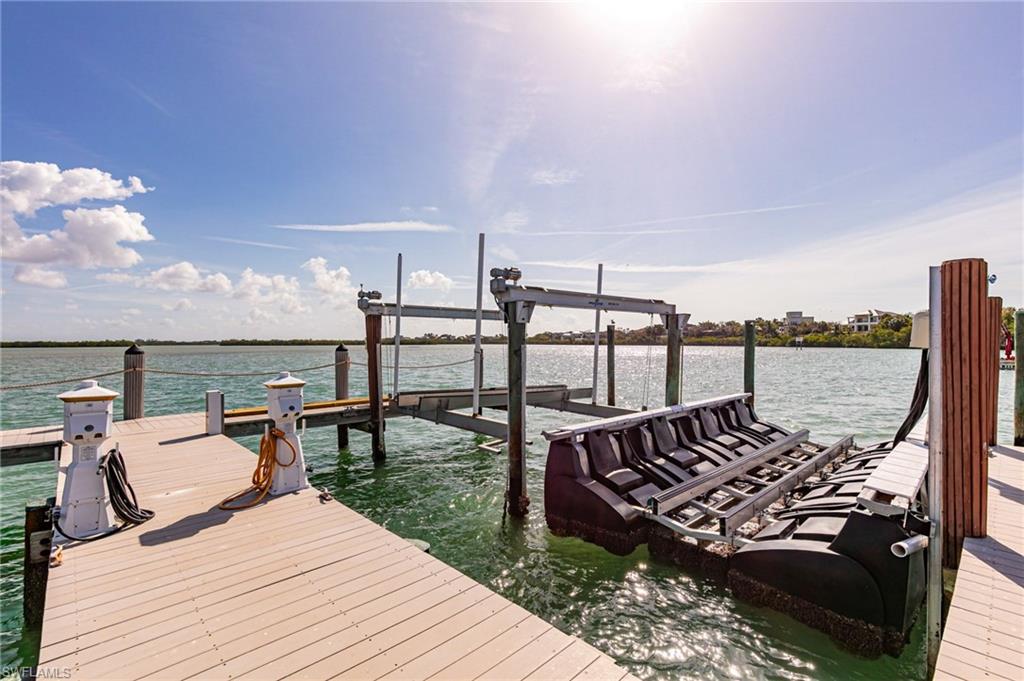 Waterfront dock featuring composite decking, multiple pilings, boat lift system, and a floating jet ski dock