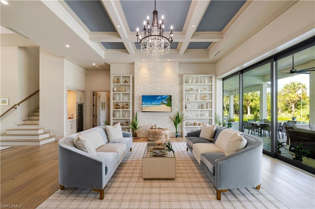 Spacious living area featuring coffered ceilings, a crystal chandelier, and a textured accent wall