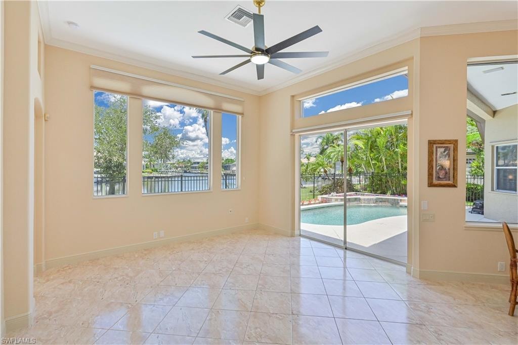 Spacious interior featuring large format tile flooring, crown molding, and a modern ceiling fan