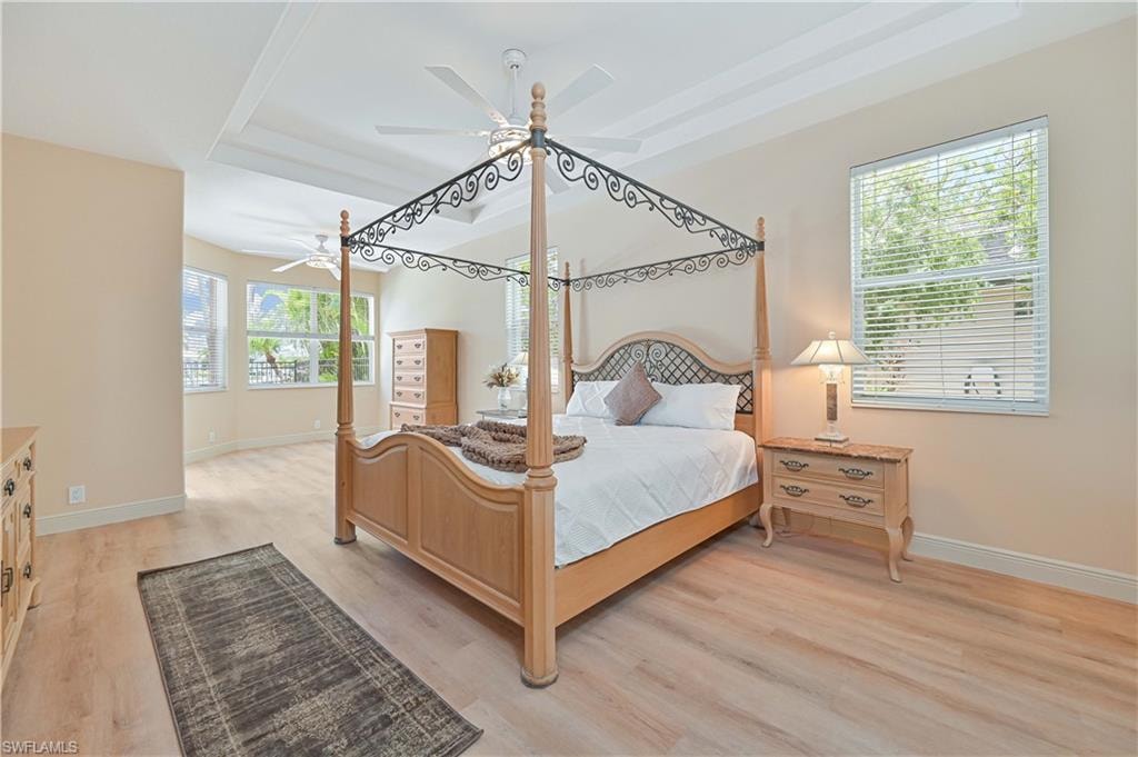 Spacious room featuring wood-finish flooring and a tray ceiling with a ceiling fan