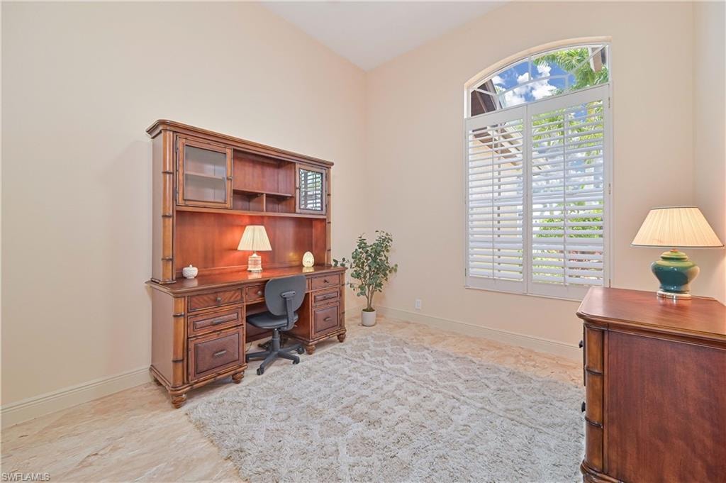 Room featuring a large arched window with plantation shutters, light-toned wall paint, and tile flooring