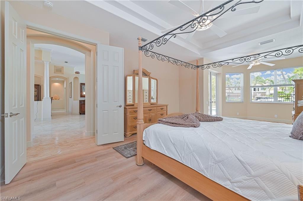 Spacious room featuring wood-finish flooring, a tray ceiling with integrated lighting, and multiple windows