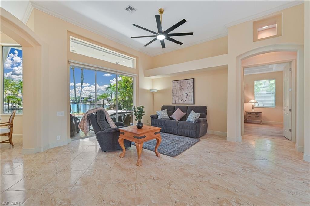 Living area featuring high ceilings, large format tile flooring, a modern ceiling fan, and sliding glass doors opening to an outdoor space with a pool