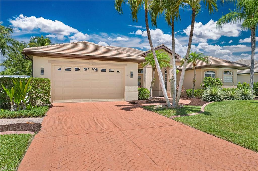 Stucco exterior featuring a tile roof, decorative garage door, and a paver driveway