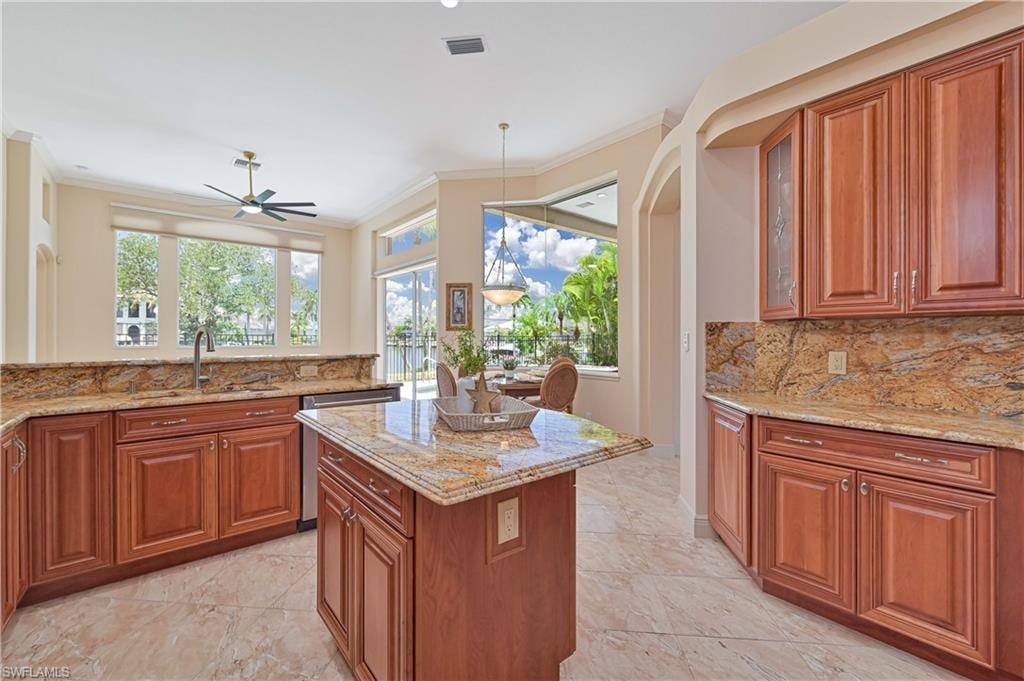 Kitchen featuring a central island with countertop, extensive cabinetry with glass-front accents, and a tile backsplash