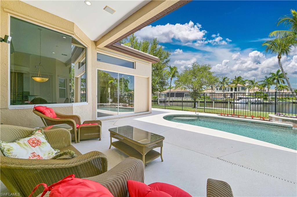 Expansive outdoor living area featuring a rectangular swimming pool, concrete patio, and a black wrought-iron fence