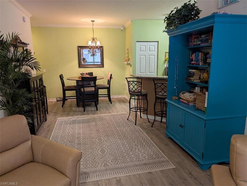 Dining room with wood finished floors, a chandelier, and ornamental molding