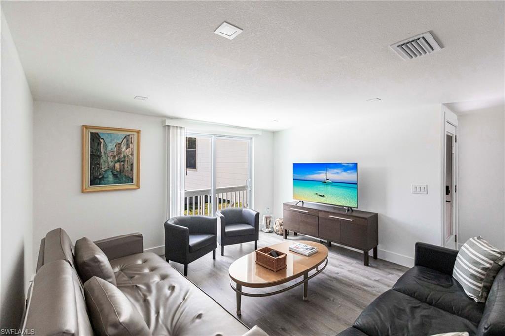 Living area featuring wood-finish flooring, recessed lighting, and a sliding glass door opening to an exterior deck