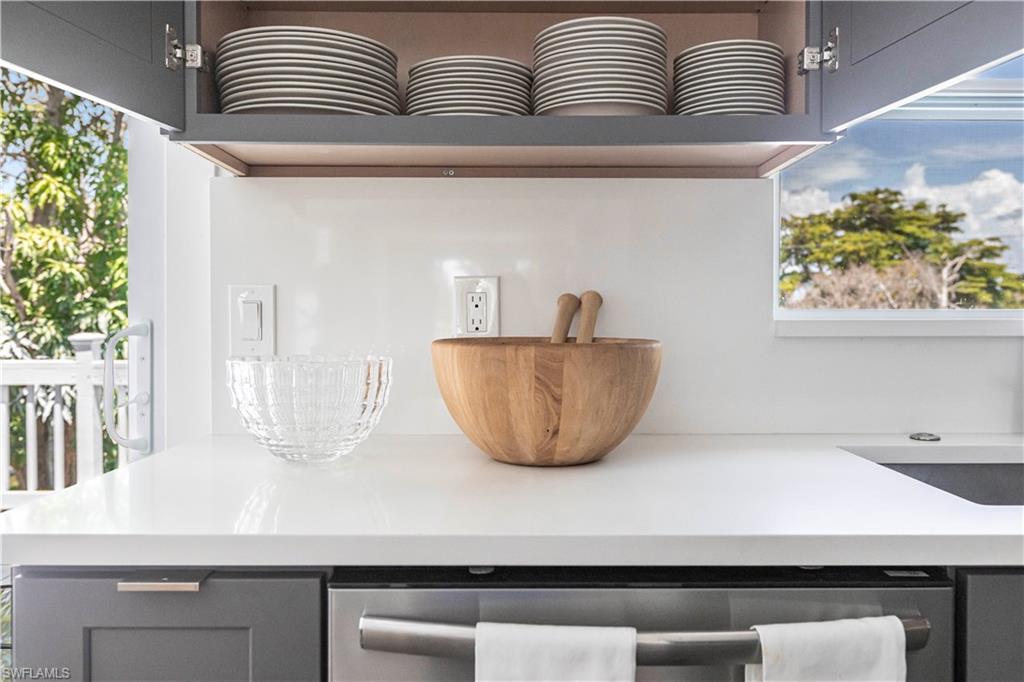 Modern kitchen featuring white countertops, grey cabinetry, stainless steel dishwasher, and a white backsplash