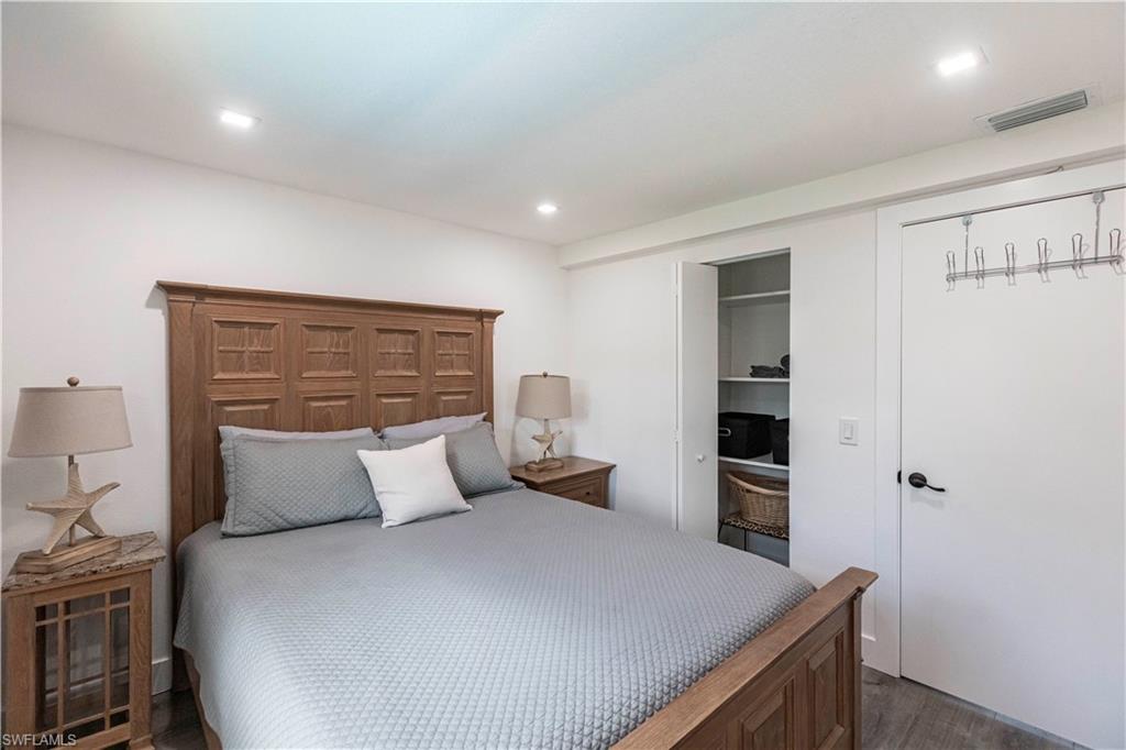 Bedroom featuring wood-finish flooring, recessed lighting, white walls, a built-in closet with shelving, and a solid core door with matte black hardware
