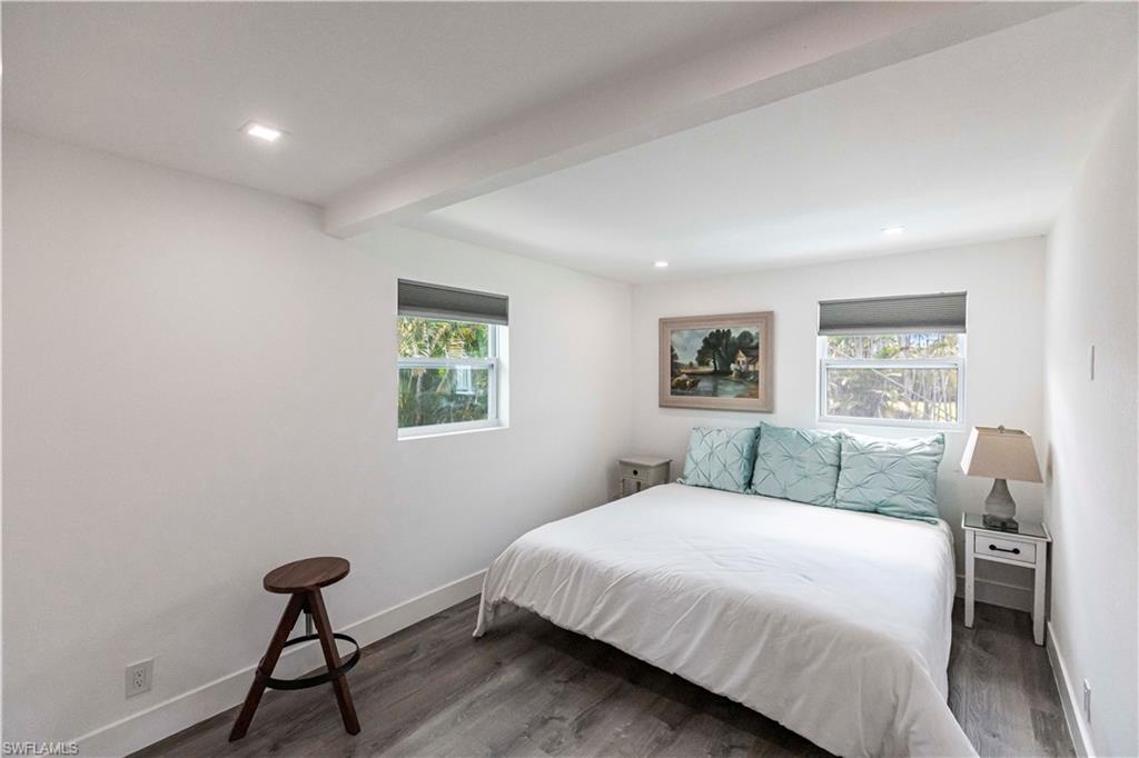 Room featuring white walls, recessed lighting, two windows with roller shades, and wood-finish flooring