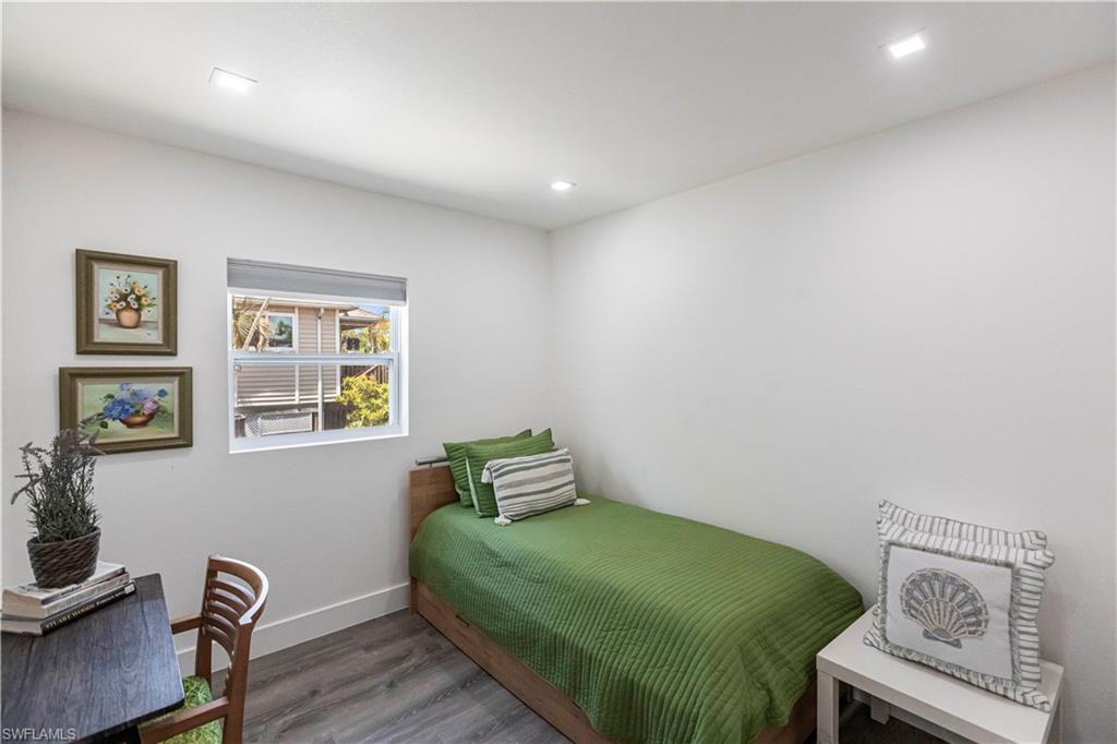 Bright interior room featuring white walls, recessed ceiling lighting, a double-hung window with privacy blinds, and wood-finish flooring