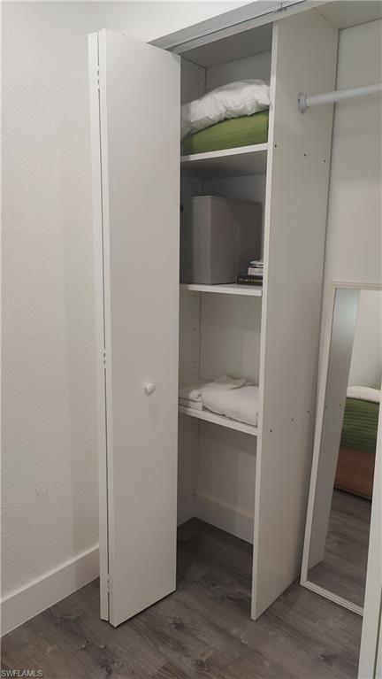White bifold closet doors opening to built-in shelving, a hanging rod, and wood-finish flooring