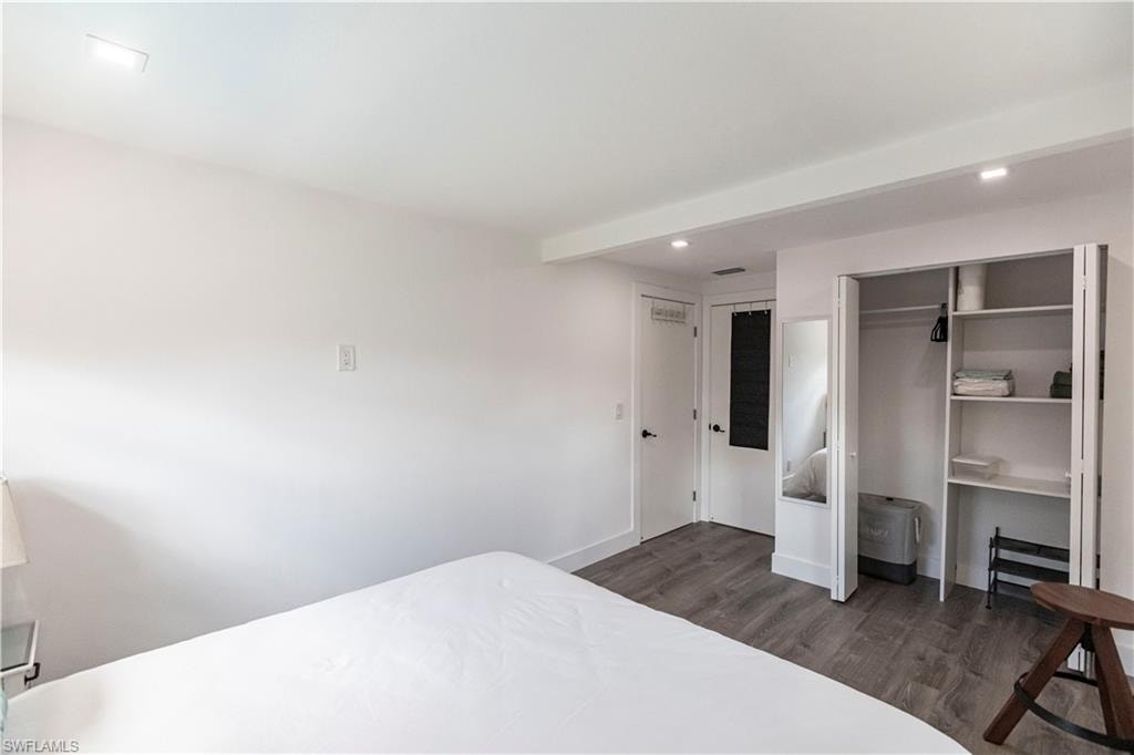 Bedroom featuring wood-finish flooring, recessed lighting, white walls, and a built-in closet with shelving