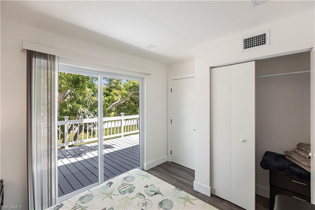 Sliding glass doors opening to an outdoor deck with white railing, featuring wood-finish flooring and a bi-fold closet door