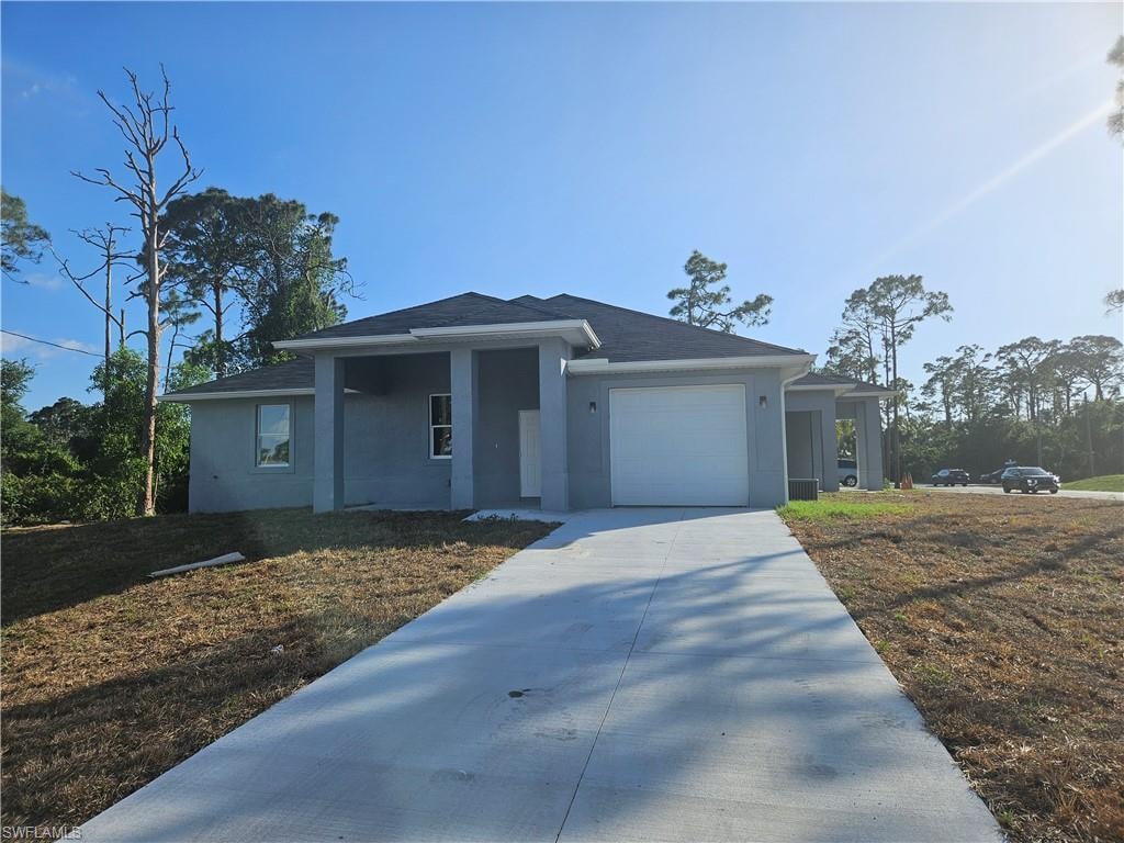 View of front of house with a garage, concrete driveway, and stucco siding