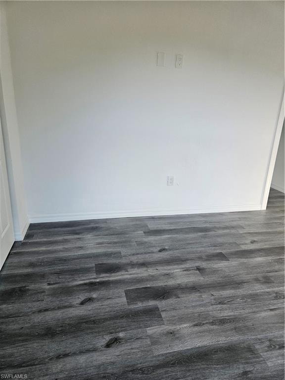 Spare room with dark wood-style floors and baseboards