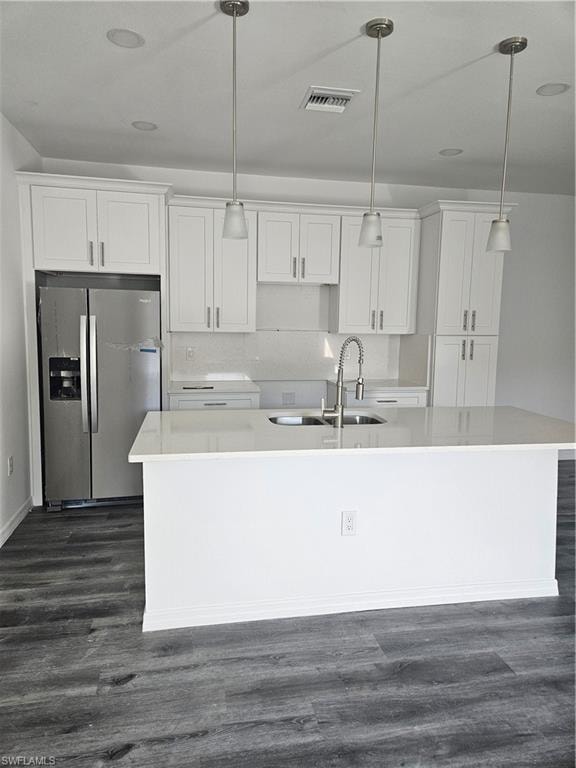 Kitchen with a kitchen island with sink, white cabinets, and refrigerator
