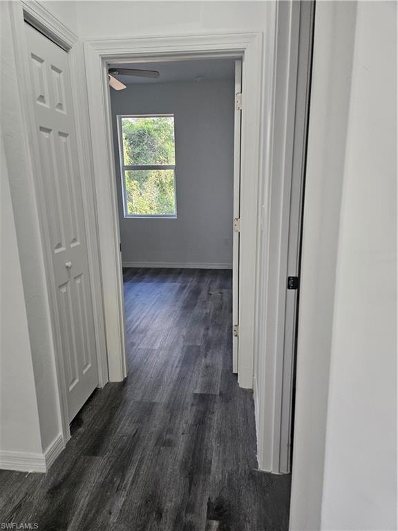 Hallway featuring dark wood-style floors and baseboards