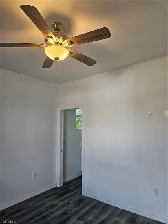 Empty room featuring dark wood finished floors, baseboards, and ceiling fan