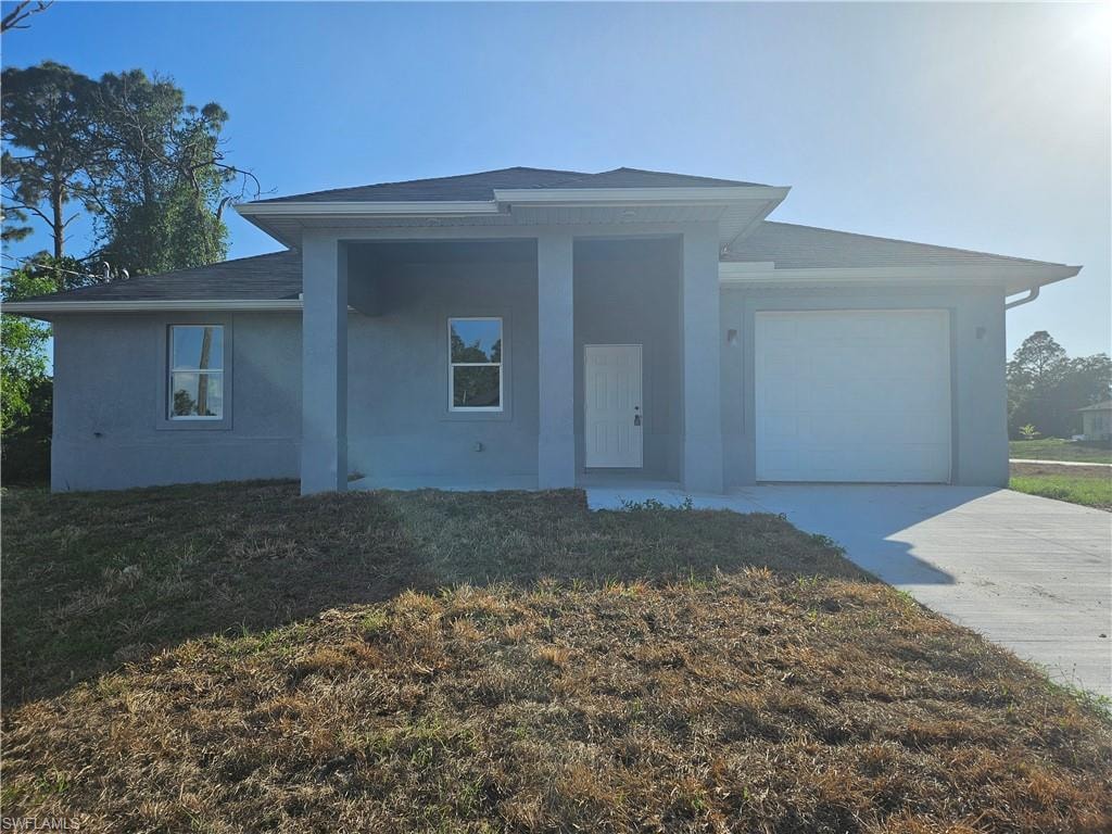 View of front facade with stucco siding, driveway, a front lawn, a garage, and a shingled roof