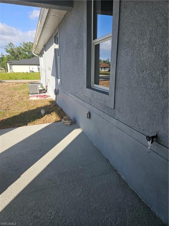 View of side of property featuring stucco siding, central air condition unit, crawl space, and a patio area