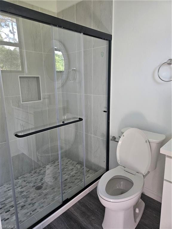 Full bath featuring wood finished floors, toilet, and a shower stall