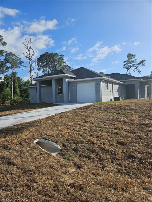 Ranch-style house featuring central air condition unit, a garage, concrete driveway, and stucco siding