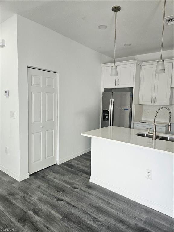 Kitchen featuring white cabinets, light countertops, refrigerator, dark wood-type flooring, and a sink
