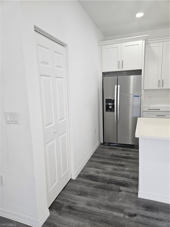 Kitchen with fridge, white cabinetry, light countertops, and dark wood-style flooring