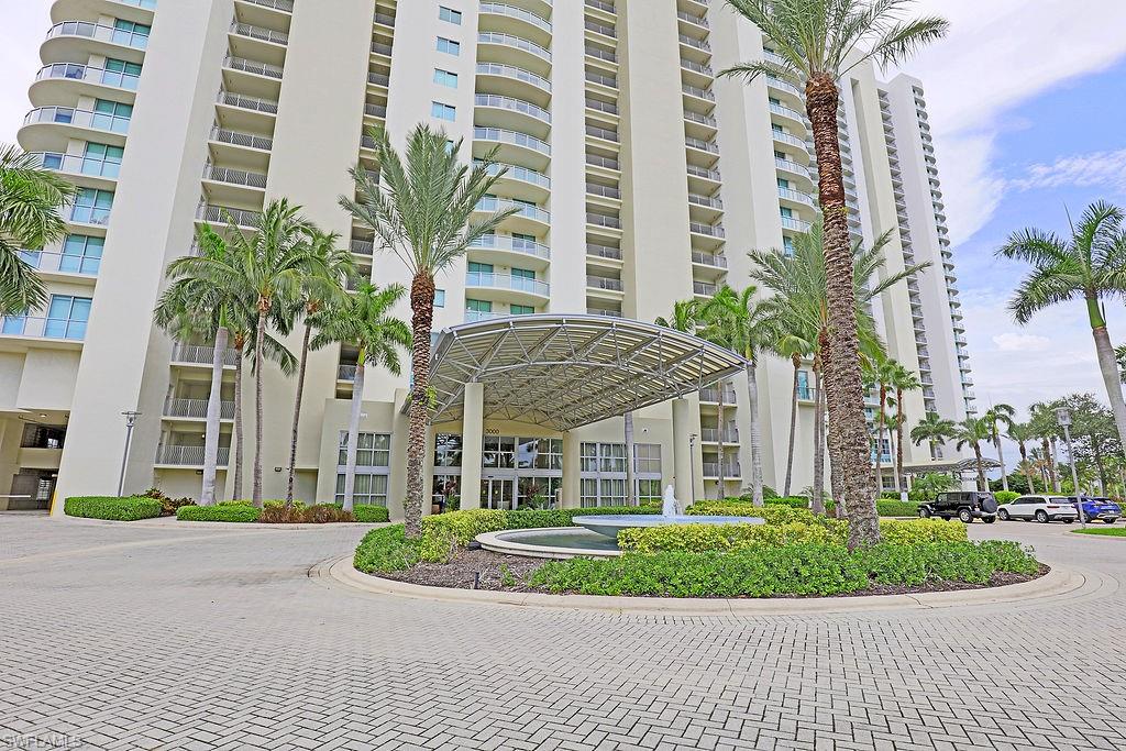 Modern high-rise residential building featuring a grand porte-cochère entrance with a contemporary canopy