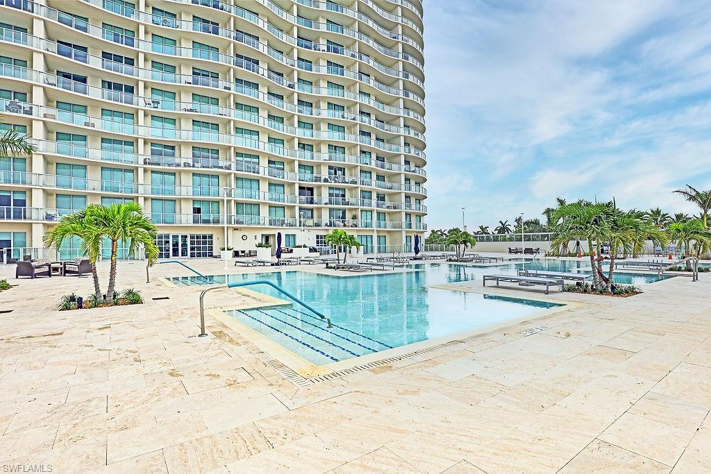 Expansive outdoor pool area with multiple interconnected pools, surrounded by light-toned pavers