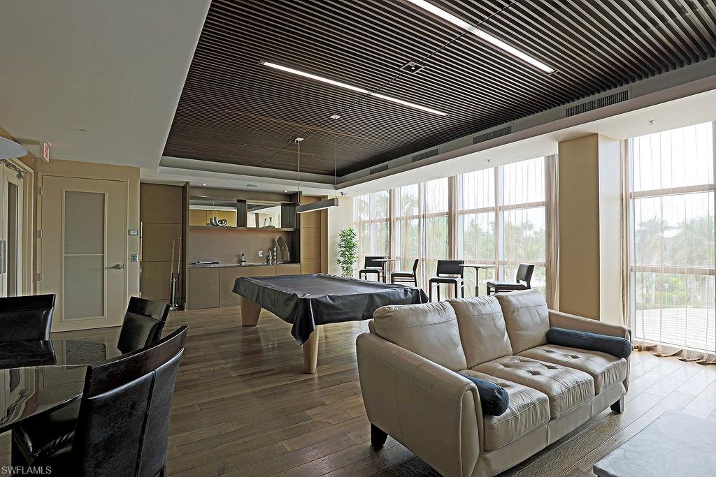 Open-concept room featuring wood-finish flooring, a full wall of tall windows, and a dark wood slat ceiling with integrated linear lighting