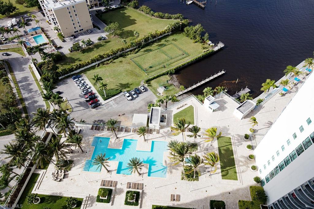 Expansive outdoor amenity deck featuring a terraced pool, surrounding lounge areas, and mature palm trees