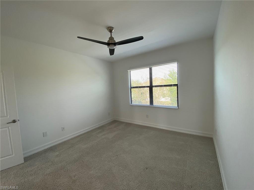 Bright interior space featuring a window with horizontal blinds, neutral wall paint, and a ceiling fan