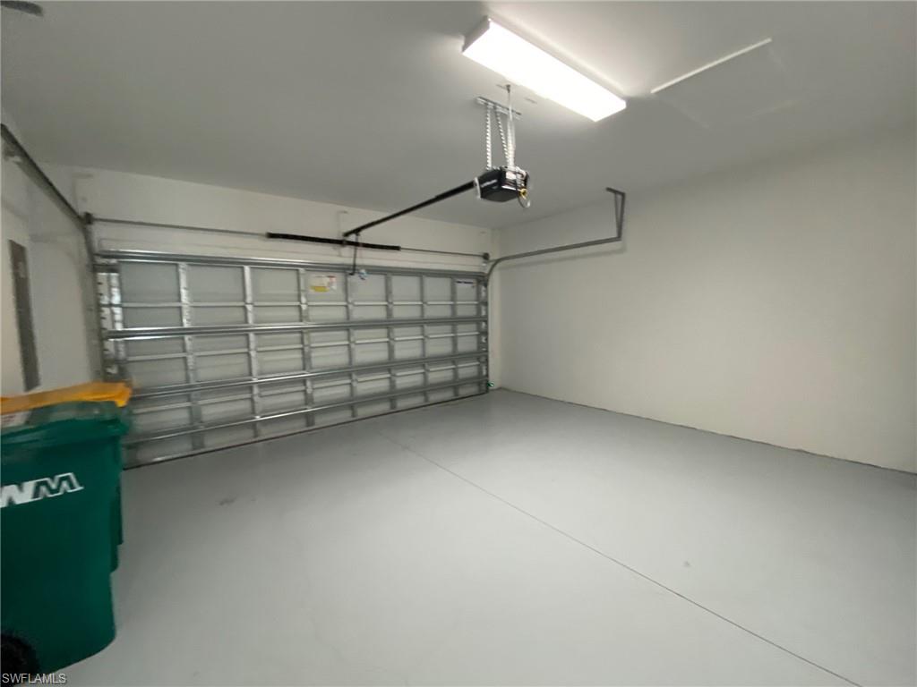 Spacious garage featuring a light gray finished floor, white painted walls, a sectional garage door, and an overhead lighting fixture