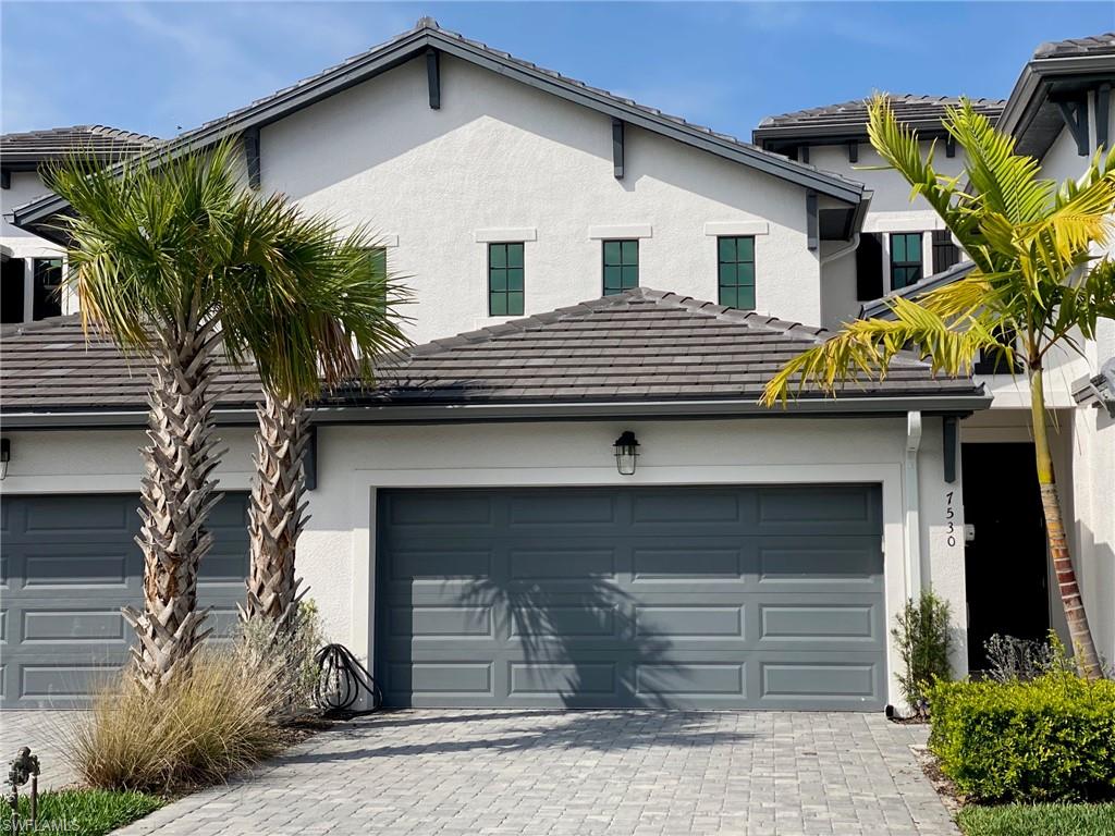 Modern exterior featuring a light stucco finish, dark gray garage doors, and a tiled roof