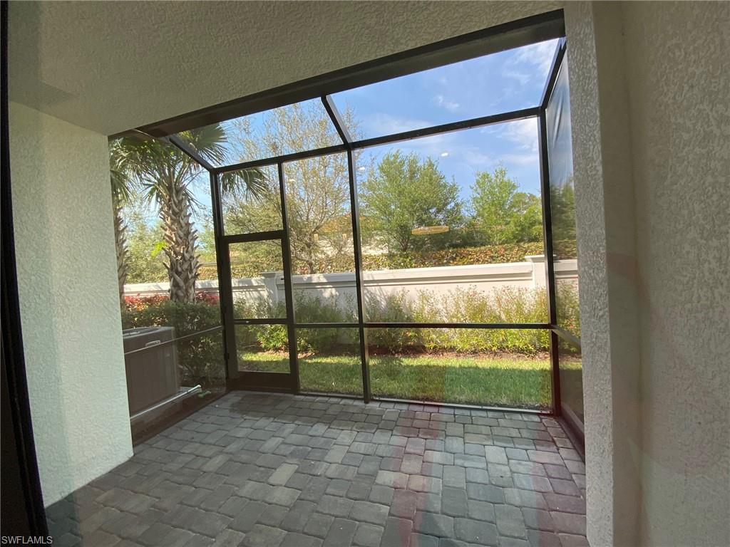 Screened-in patio featuring paver flooring, a vaulted screen enclosure, and a landscaped exterior with mature trees