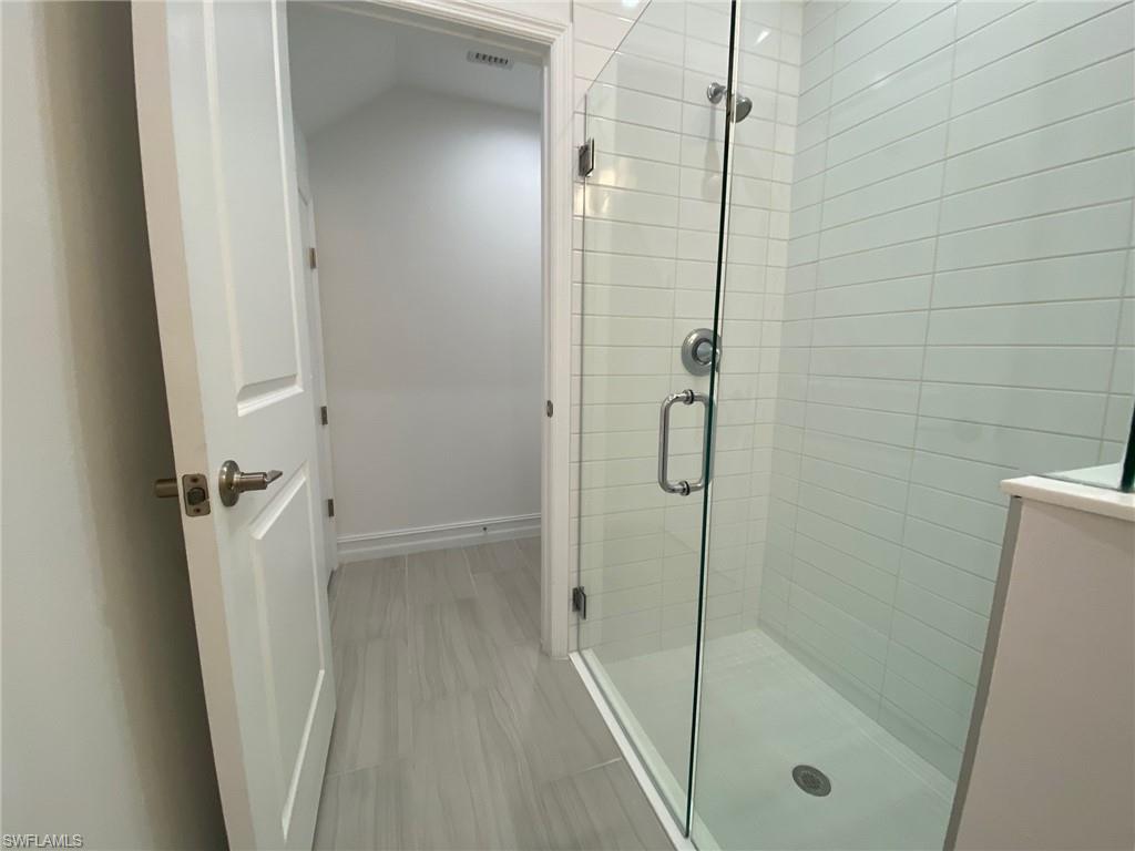 Modern bathroom featuring a frameless glass shower enclosure, white subway tile shower surround, and a chrome shower fixture