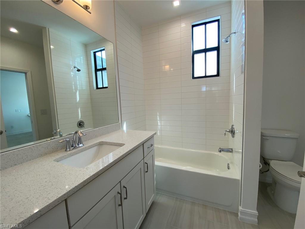 Bathroom featuring a single vanity with a quartz-finish countertop, undermount sink, and chrome fixtures
