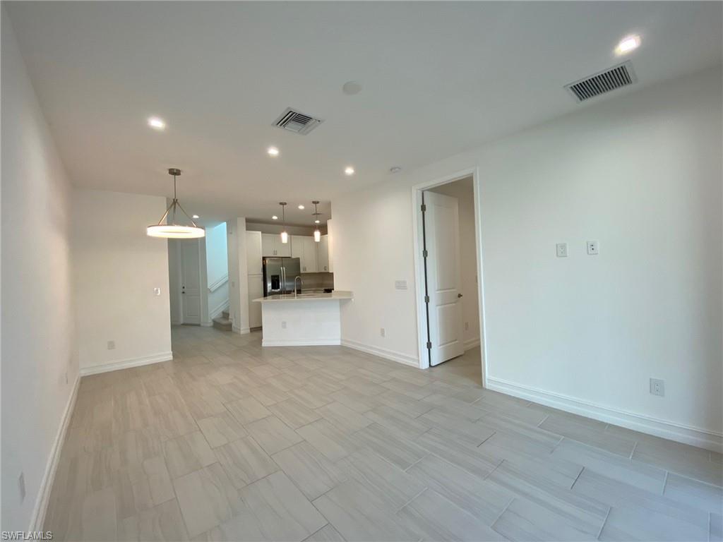Open-concept living area featuring light-toned tile flooring, recessed lighting, and a contemporary pendant fixture