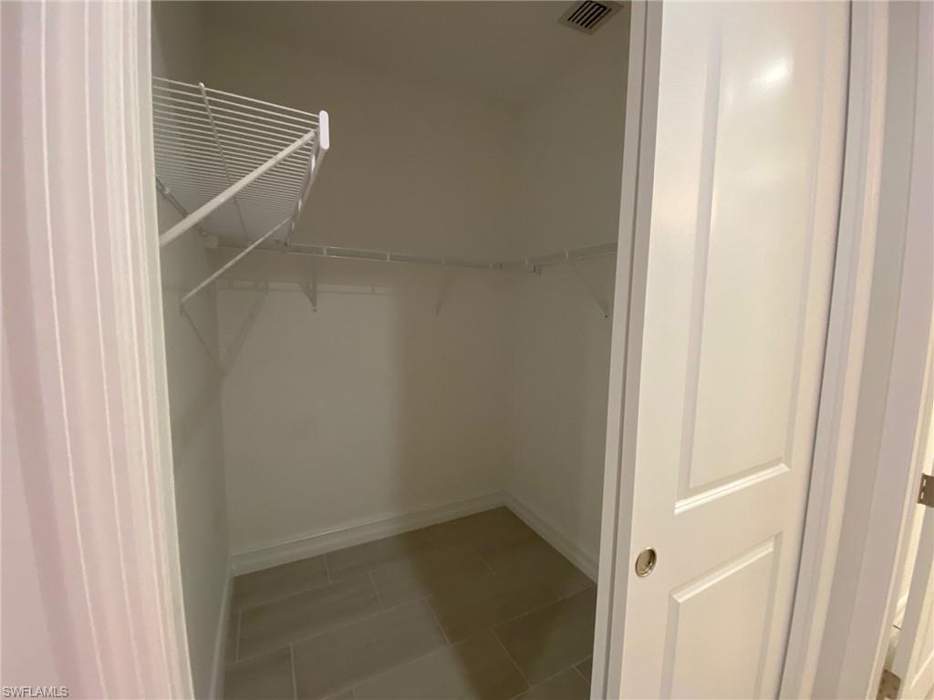 Recessed walk-in closet featuring light-toned tile flooring, white wire shelving, and a white interior door with a silver-tone handle