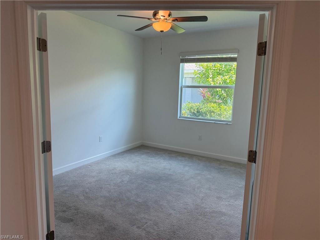 Room with neutral wall paint, gray carpet flooring, a window with horizontal blinds, and a ceiling fan with light fixture