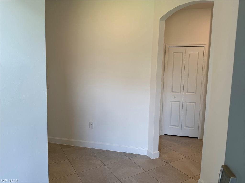 Arched doorway featuring a bifold door and tiled flooring