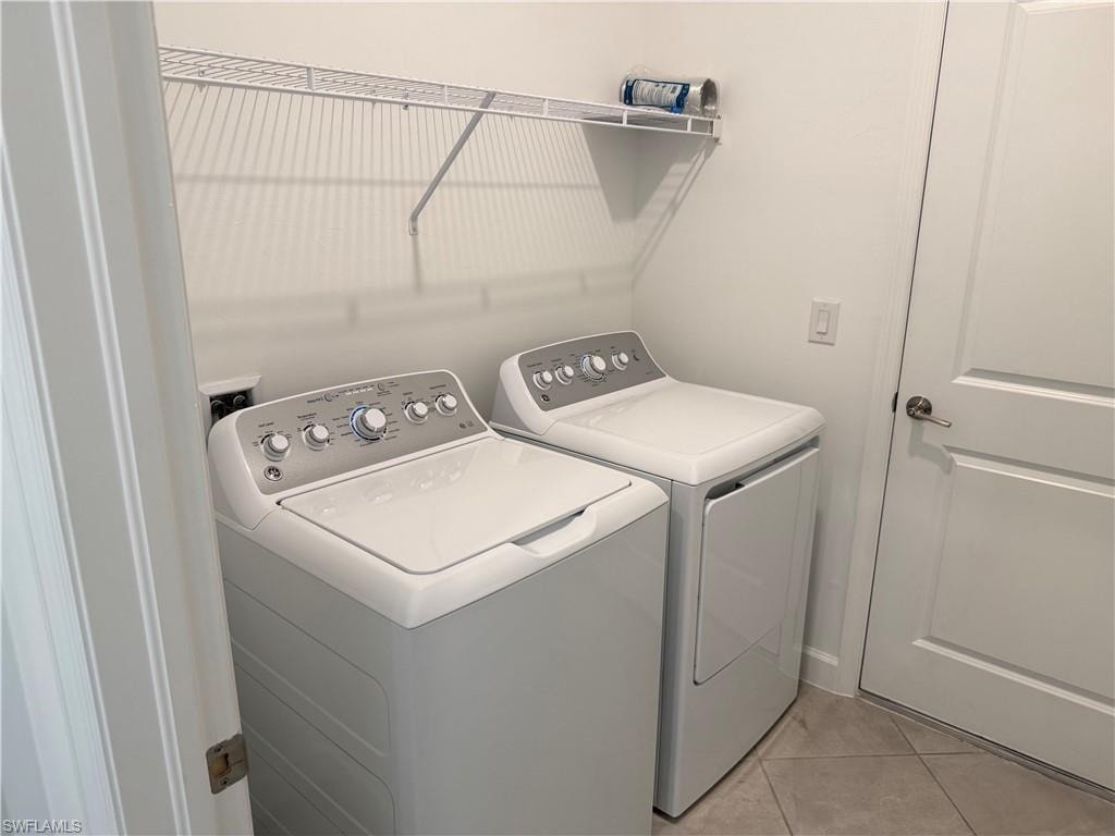 Dedicated laundry space featuring a white wire shelving unit and tile flooring
