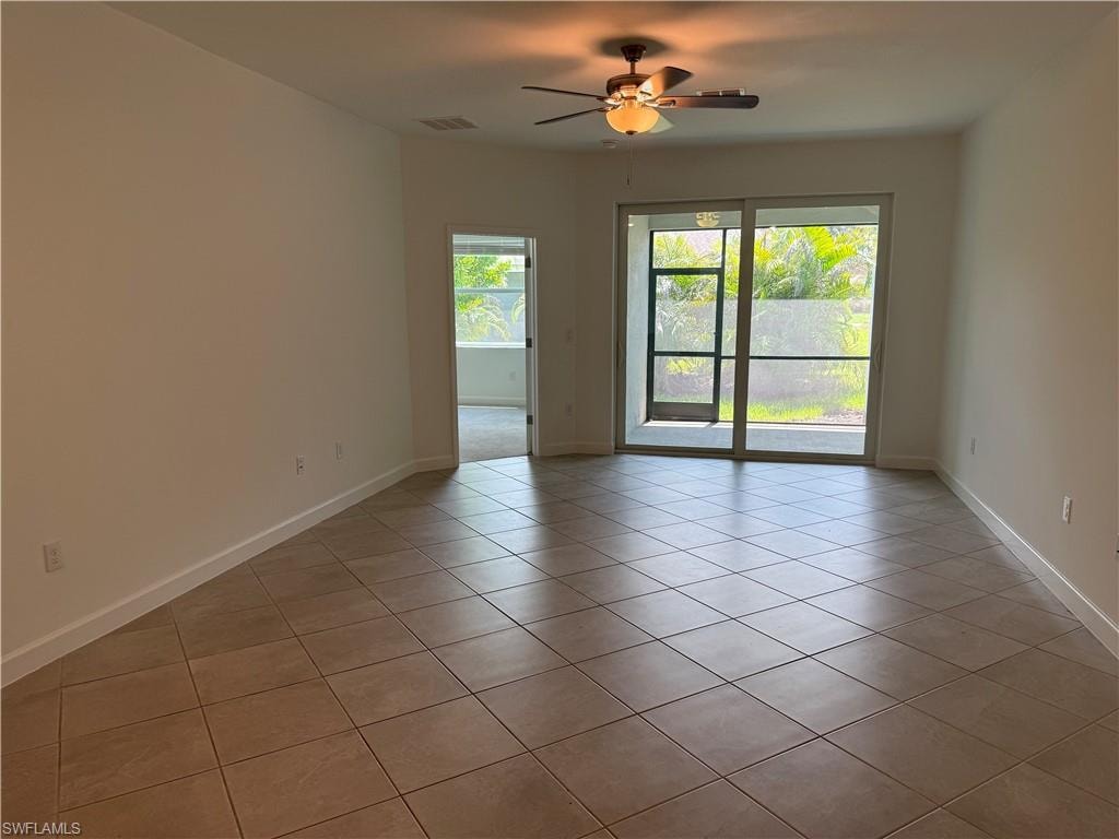 Open living area featuring neutral tile flooring, light-toned walls, and a ceiling fan with integrated lighting